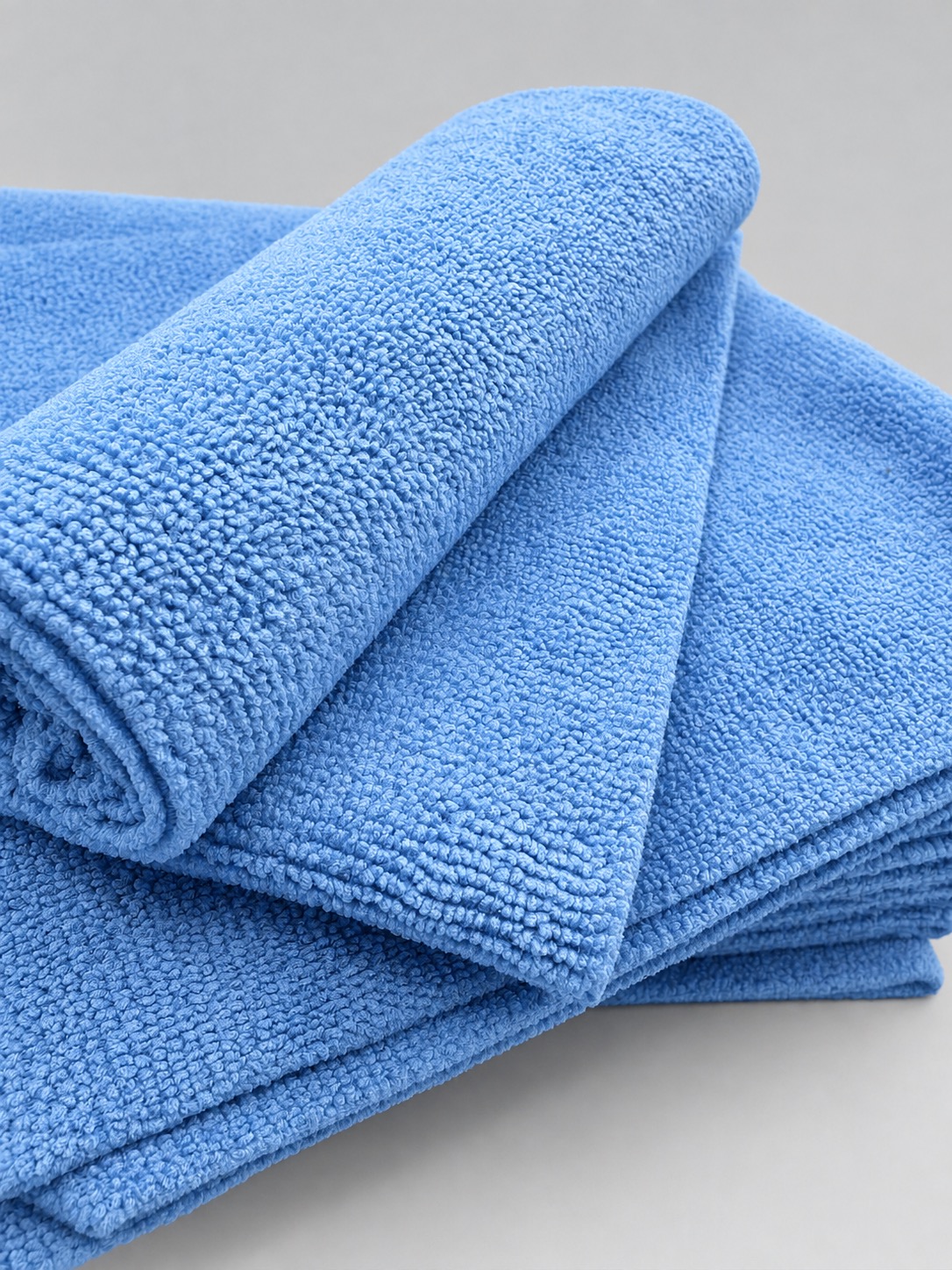Blaues randloses Mikrofasertuch gerollt auf dem Set
